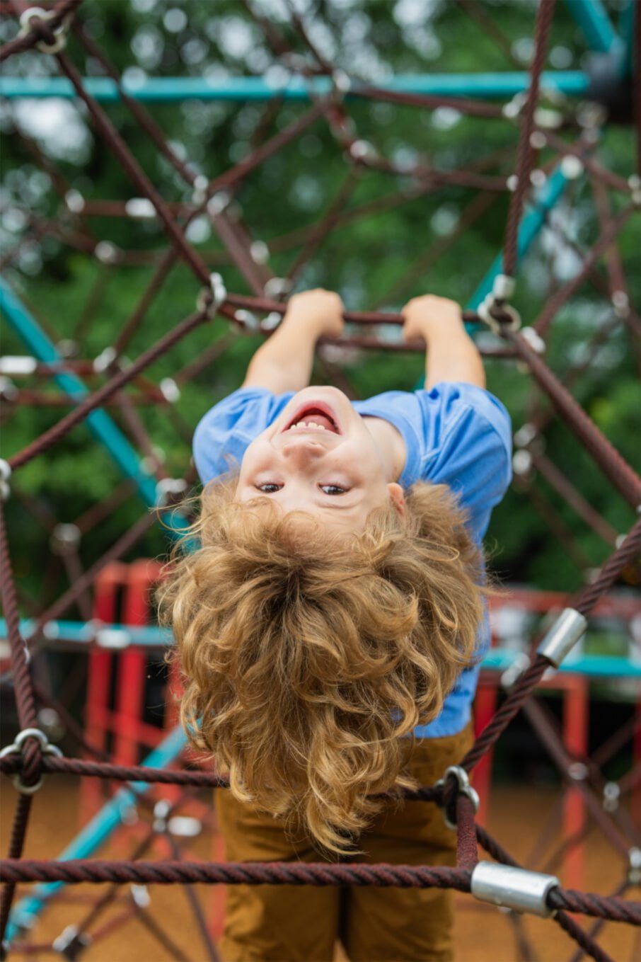 The,Child,Is,Hanging,Upside,Down,On,The,Playground,Equipment.